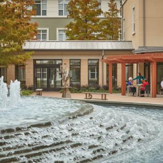 A serene courtyard with a flowing fountain surrounded by autumn trees and buildings.