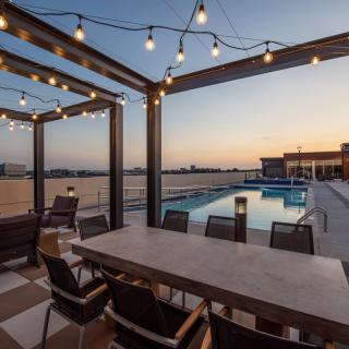 A cozy outdoor patio with string lights overlooking a pool at sunset.