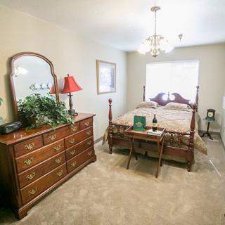 A cozy bedroom with a wooden dresser and a neatly made bed.