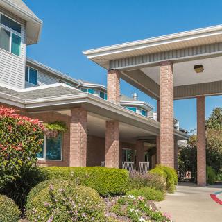 A view of a modern residential building entrance with well-maintained landscaping.