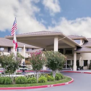 A large building entrance with flags and landscaped surroundings.