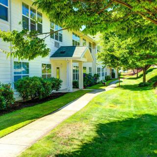 A picturesque view of apartment buildings surrounded by lush greenery and a neatly maintained lawn.