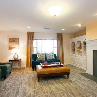 A cozy living room with comfortable seating, decorative shelves, and a large window providing natural light.