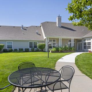 A peaceful backyard view with a table and chairs on a sunny day.