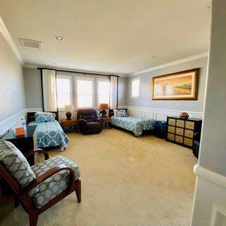 A spacious bedroom with two twin beds, armchairs, and ample natural light.