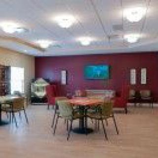 A spacious lounge area with tables, chairs, and a TV on the wall.