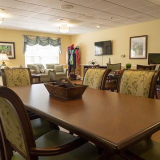 A spacious dining room with a large wooden table and chairs, featuring cozy decor and natural lighting from a window.
