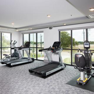 A modern gym with various exercise equipment including treadmills and stationary bikes.