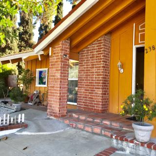 A welcoming house entrance with brick pillars and a small porch adorned with potted plants.