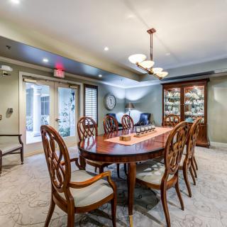 An elegant dining room with a polished wooden table, chairs, and a chandelier overhead.