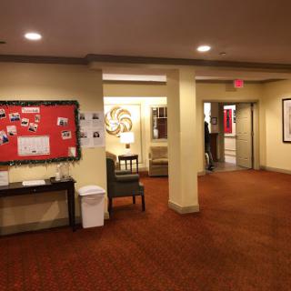 A view of a well-lit hallway with a community bulletin board and seating area.
