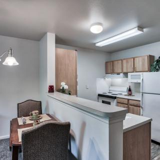 A cozy kitchen and dining area featuring modern appliances and a small dining table with chairs.