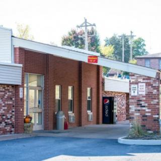 An exterior view of a roadside motel with a brick facade and nearby parking area.