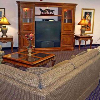 A cozy living room featuring a large sofa, an entertainment center with a television, lamps, and decorative elements.