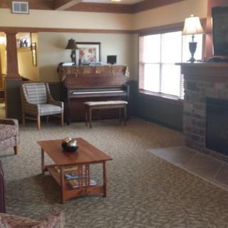 A cozy living room with a piano, fireplace, and comfortable seating.