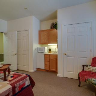 A cozy bedroom with a bed, chair, and built-in wardrobes.