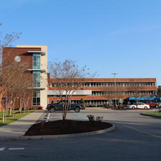 A modern architectural building with a parking lot, captured on a clear day.
