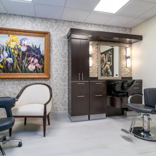 A modern salon interior with stylish chairs, a mirror, and colorful artwork on the wall.