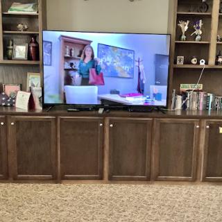 A cozy living room featuring a television display and wooden cabinetry.