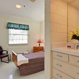 A cozy hospital or patient room featuring a bed, nightstand, and a window with natural light.