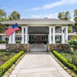 Main entrance of a residential building with an American flag and landscaped garden.