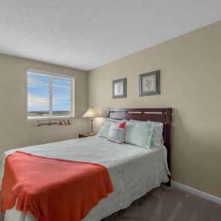 A cozy bedroom with a neatly made bed, featuring soft colors and natural light coming through the window.