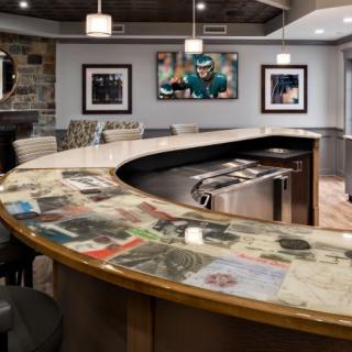 A modern bar interior featuring a curved countertop with embedded images, stylish seating, and contemporary artwork on the walls.