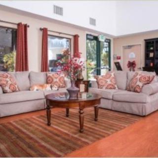A cozy living room with a sectional sofa, decorative pillows, and a wooden coffee table on a striped rug.
