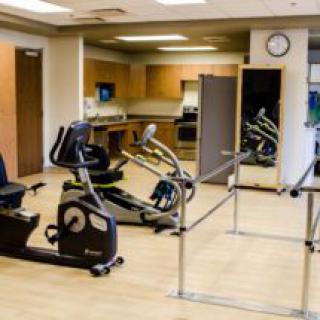 A rehabilitation gym equipped with a stationary bike and parallel bars.