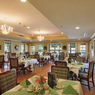 An elegant dining room with neatly arranged tables and chairs, adorned with chandeliers and decor.