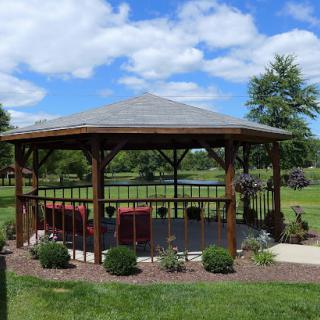 A charming gazebo surrounded by greenery on a sunny day.