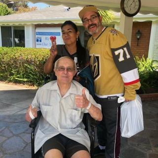 A smiling group poses outdoors with one person in a wheelchair.