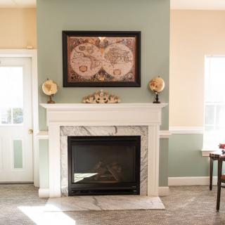 A cozy living room with a classic marble fireplace, adorned with artwork and decorative items.