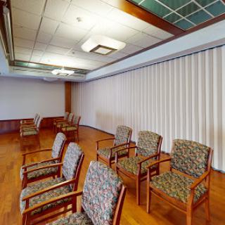 A spacious waiting room featuring patterned chairs and wooden flooring, offering a comfortable environment.