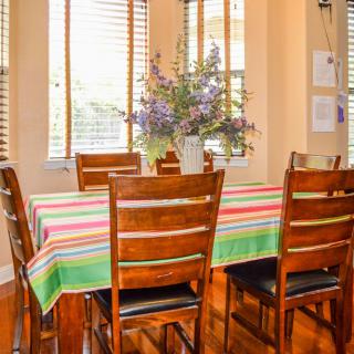 A cozy dining room with a colorful tablecloth and a bouquet of flowers on the table.