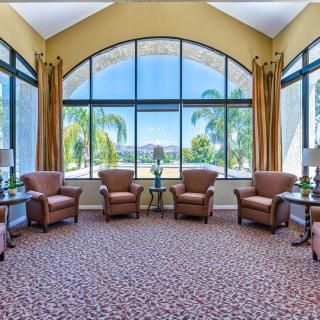 A spacious lounge area with comfortable chairs and large windows overlooking palm trees.