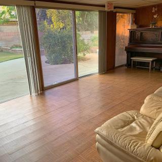 A cozy living room with a piano, sliding glass doors, and a comfortable sofa.