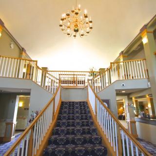 Elegant hotel lobby featuring a grand staircase and chandelier.