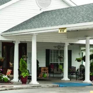 A building entrance with white columns, a porch, and decorative plants.
