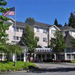 A hotel building with trees in front and an American flag waving on a sunny day.