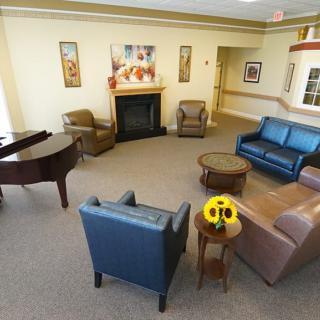 A cozy living room with a fireplace, comfortable seating, and a piano.