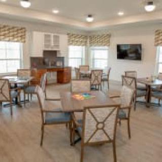 A well-lit dining room with neatly arranged tables and chairs.