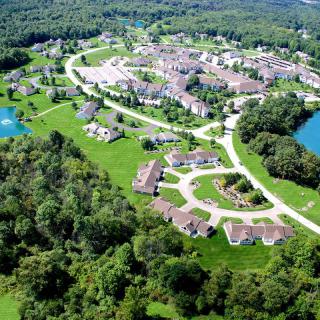 Aerial view of a residential community surrounded by lush greenery and small lakes.