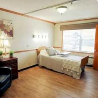 A cozy bedroom with a single bed, large window, and comfortable furnishings.