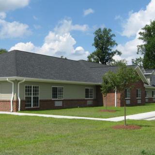 A suburban house with a neatly maintained lawn under a clear blue sky.