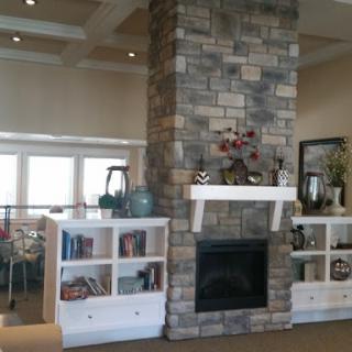 A cozy living room featuring a stone fireplace and stylish bookshelves.
