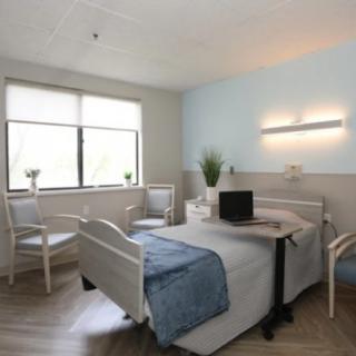 A modern and clean hospital room with a neatly made bed and natural light filtering through the window.