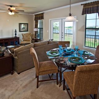 A cozy living and dining area with a sofa, dining table set, and large windows allowing natural light to illuminate the space.