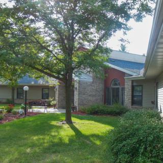 A well-maintained residential house with a green lawn and tree.