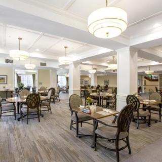 Spacious dining area with multiple tables, elegant lighting, and neutral decor.